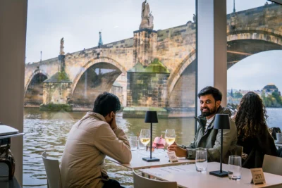 Corporate dinner by the Vltava River with Charles Bridge view, showcasing real MICE Prague experience outside conference rooms