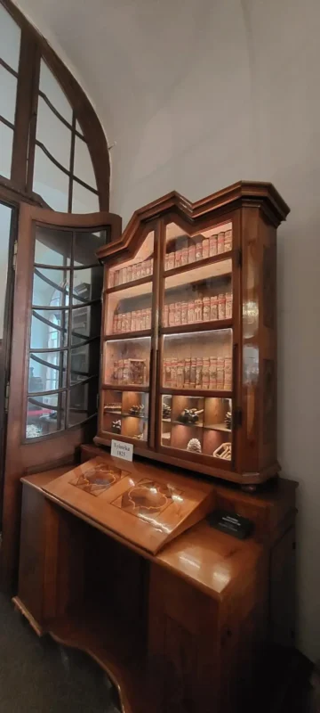 Exhibit inside the Strahov library showing an antique wooden cabinet labeled “Xylotéka 1825,” filled with historical botanical samples and neatly arranged specimen boxes.